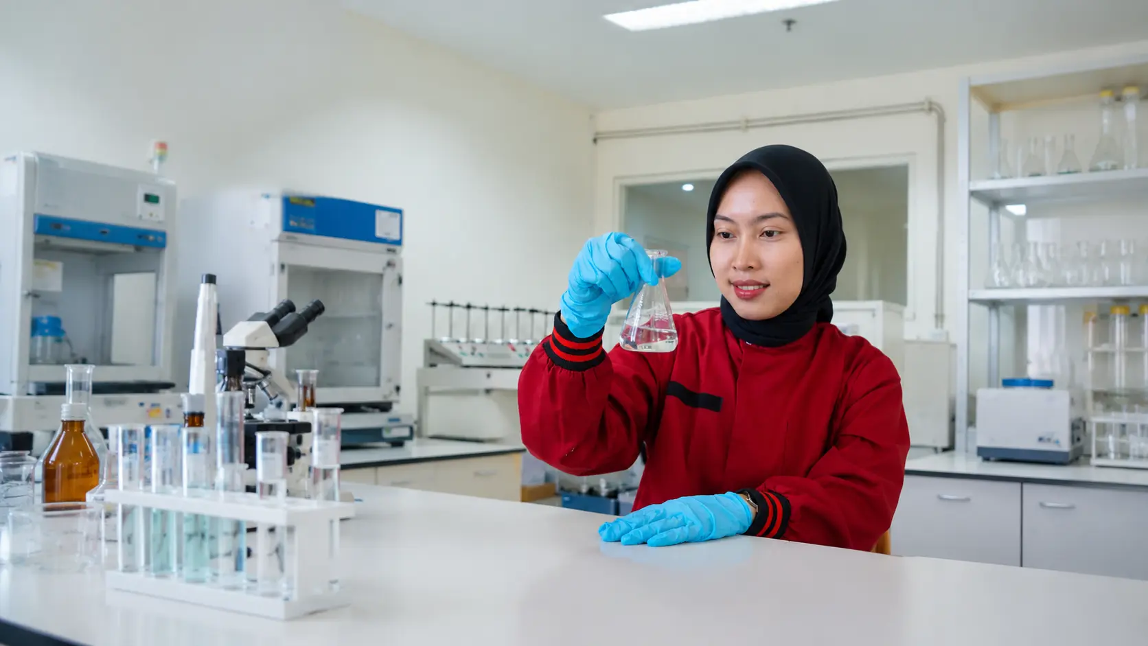 Teknisi laboratorium lingkungan wanita sedang melakukan analisis sampel cairan di laboratorium modern dengan peralatan pengujian profesional